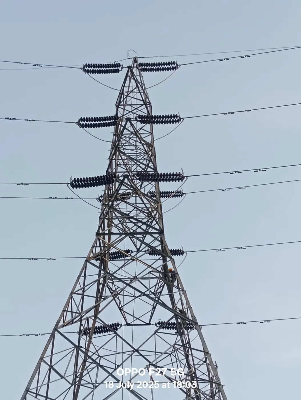 High-voltage transmission tower against the sun